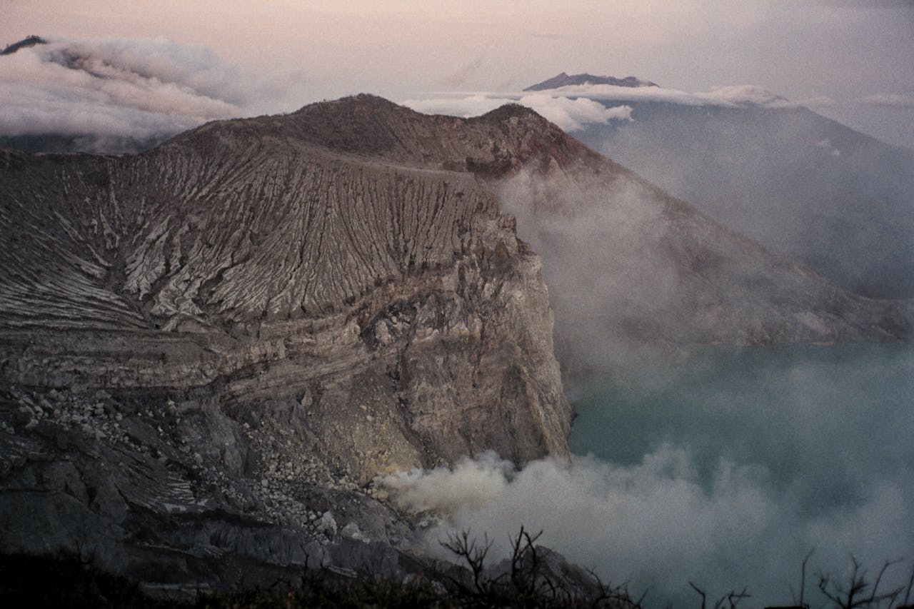 A stunning volcanic crater with steaming vents and rugged terrain under a twilight sky.